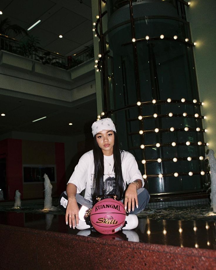 a woman sitting on top of a counter next to a pink ball with the word miami written on it