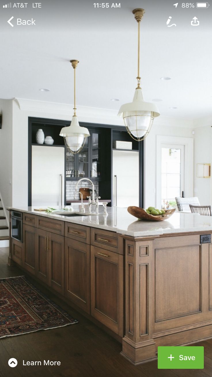 a large kitchen with an island in the middle and stairs leading up to the second floor