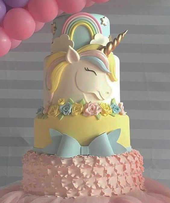 a three tiered cake with an unicorn on top