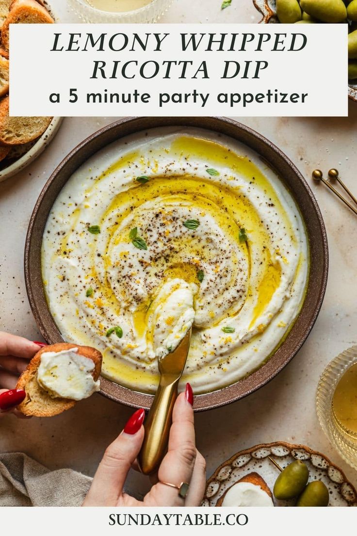 lemony whipped ricotta dip in a bowl with olives and bread on the side