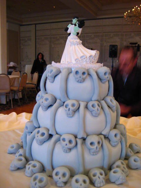 a wedding cake made to look like it is stacked with skulls and bride's dress