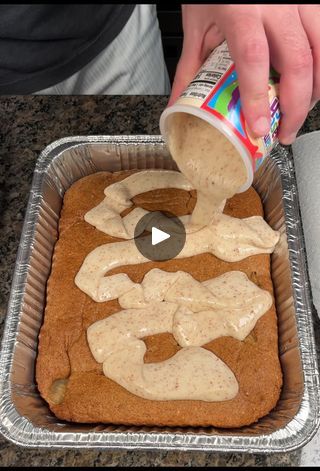 a person pouring sauce on top of a cake in a baking pan with other food items