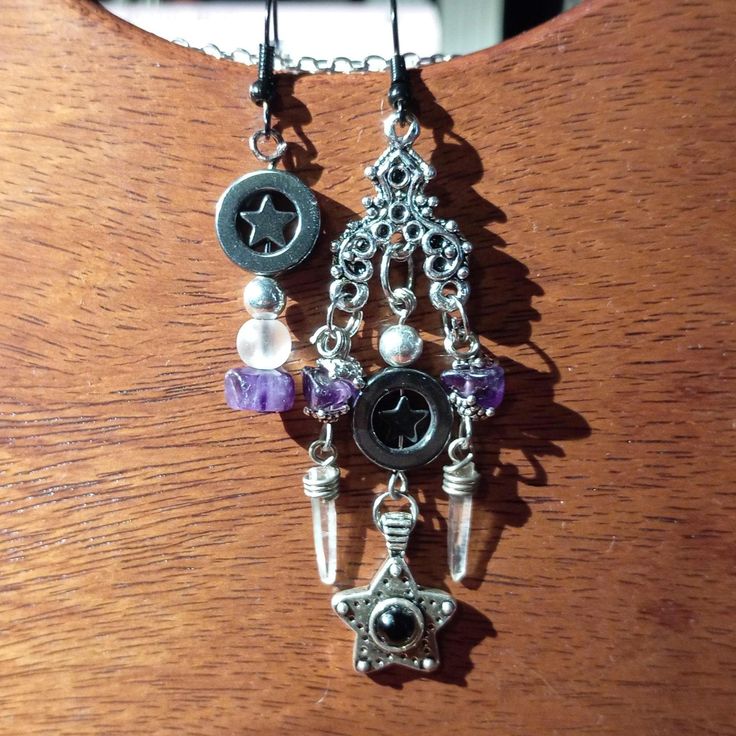 a pair of earrings with charms hanging from them on a wooden table next to a window