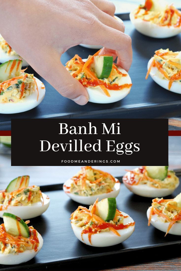 deviled eggs stuffed with cheese and vegetables are on a black tray, being held by a hand