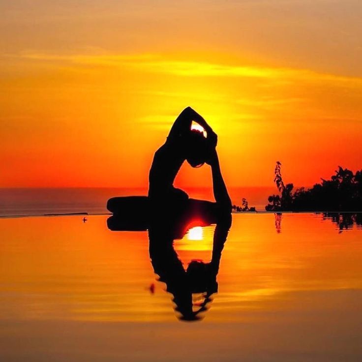 the silhouette of a person doing yoga in front of a sunset