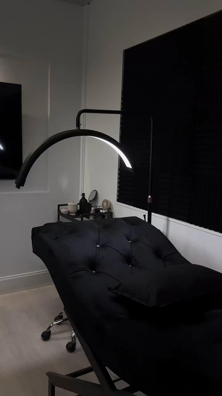 a black couch sitting in front of a flat screen tv mounted on the side of a wall