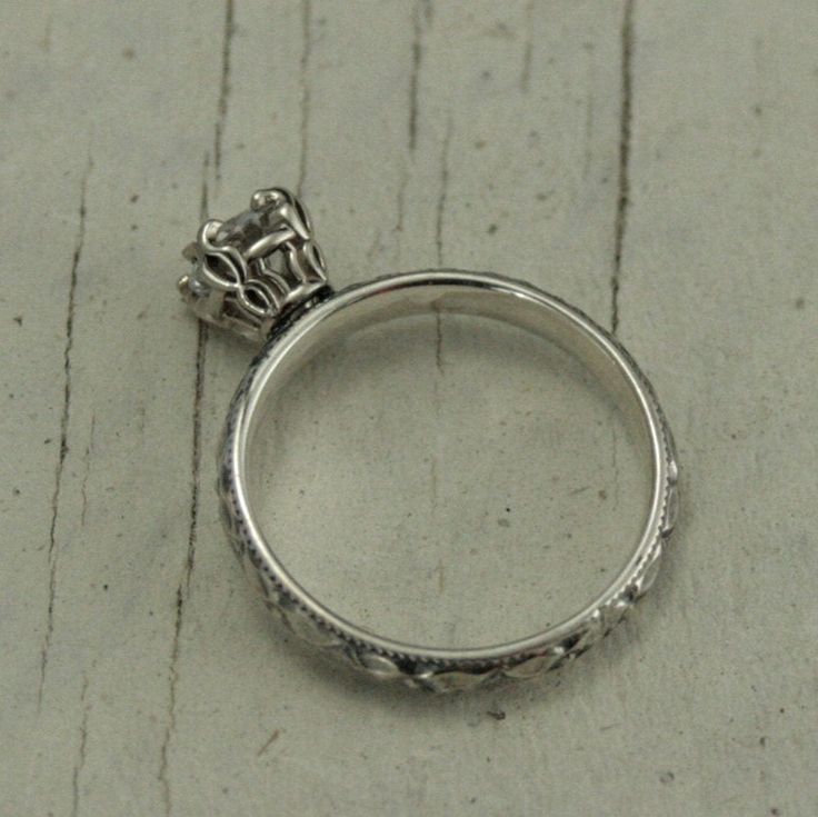 This is a lovely antique style handmade setting using our Renaissance style pattern. The shank of the engagement ring is sterling silver preformed pattern wire with a milgrain edge. It measures 2.95mm wide by 1.55mm thick. It features a 5mm genuine clear stone of your choice set in a solid 14K white gold double prong basket setting. It is then oxidized for an antique look and given a meticulous high polish by hand. For just the band: https://www.etsy.com/listing/216715890 Moissanite is an eco-fr White Sapphire Engagement Ring, Clear Stone, White Sapphire, White Ring, White Topaz, Antique Style, Prong Setting, Topaz, Vintage Style