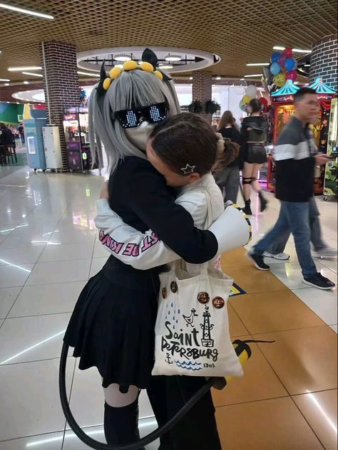 two people hugging each other in the middle of a shopping mall with balloons hanging from the ceiling