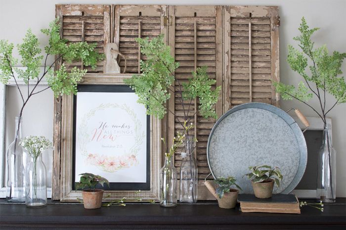 there are plants and vases on the mantle in front of an old shuttered window