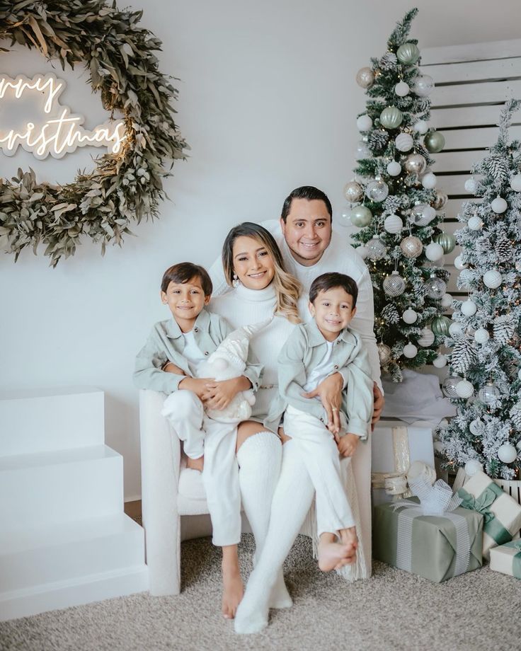 a man and two children sitting on a couch in front of a christmas tree