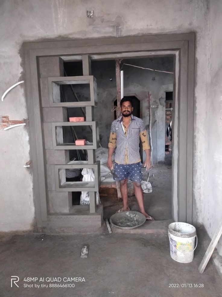 a man standing in the doorway of a building with cement on the floor and walls