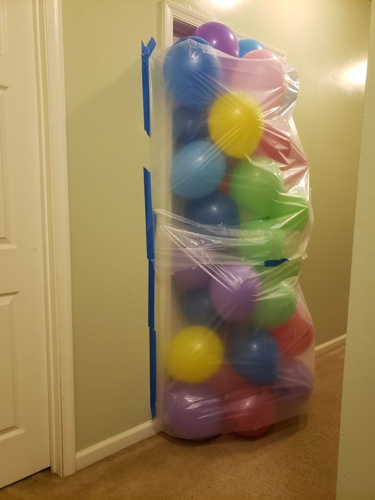 a plastic bag filled with colorful balls sitting in front of a white door on the floor