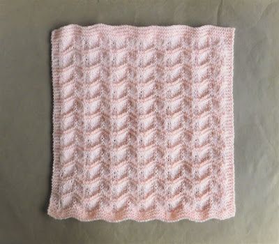 a pink knitted blanket sitting on top of a table