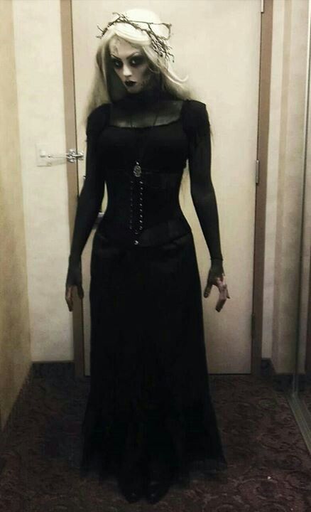 a woman dressed in black is standing in the hallway with her hands on her hips