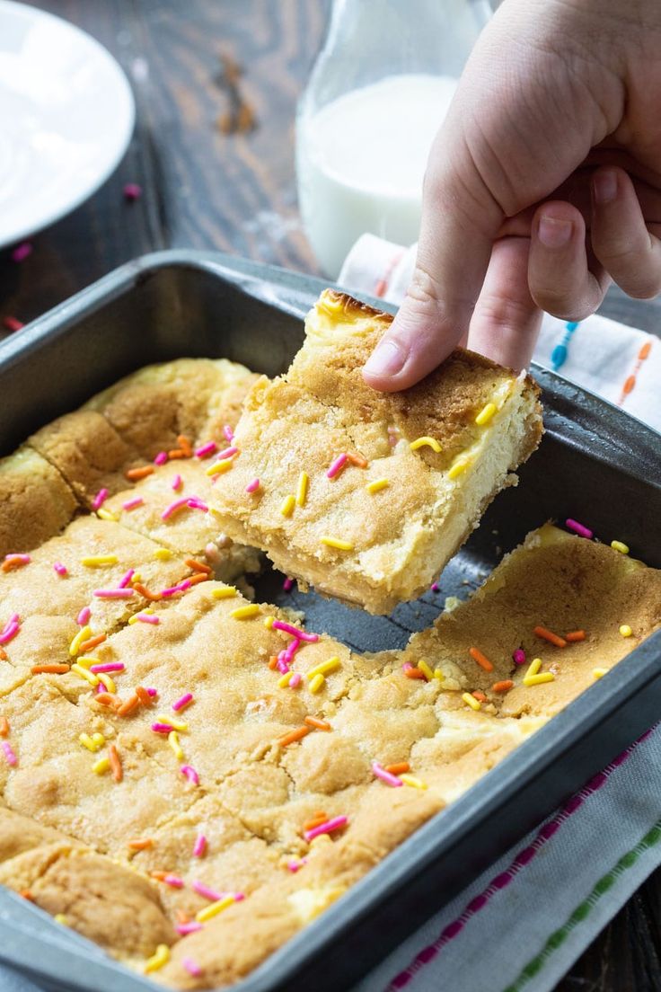 a person is taking a piece of cake out of a pan with sprinkles