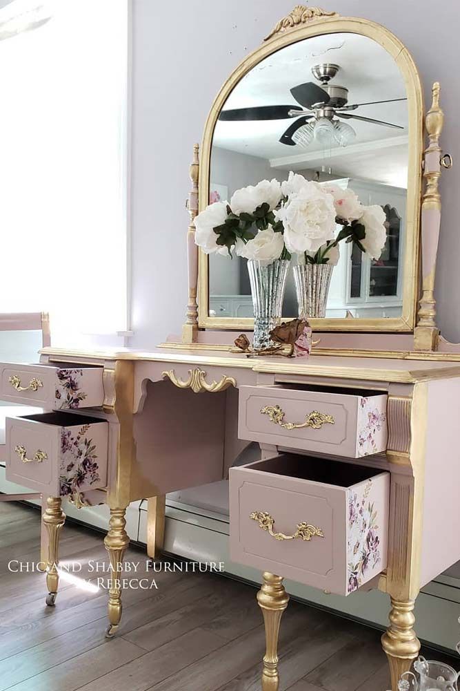 a pink and gold vanity with flowers in vases