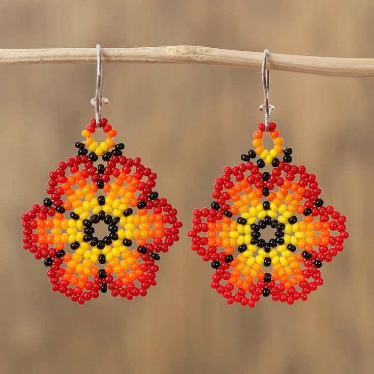 This impressive pair of dangle earrings from Mexico features the image of two flowers that blaze with hues of red orange and yellow. Using the skills that she learned from her parents and grandparents Adriana Trejo handcrafts this accessory diligently applying petite glass beads by hand. Each earring dangles from a hook of sterling silver. Huichol Flower Earrings, Seed Beading, Beaded Headband, Colorful Jewelry, Beaded Jewelry Patterns, Just Because Gifts, Glass Flowers, Beaded Dangle Earrings, Beading Tutorials