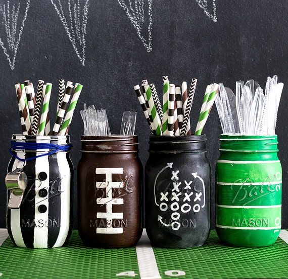 four mason jars with straws in them on a green tablecloth next to a chalkboard