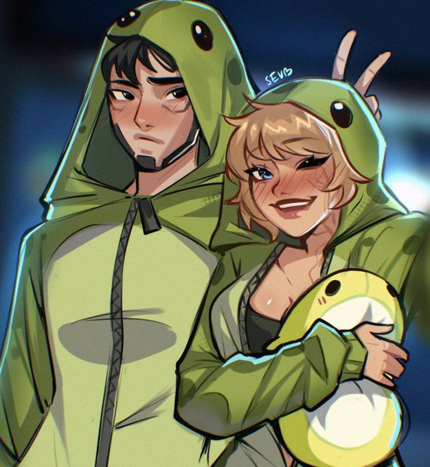 two people dressed in green and one is holding a stuffed animal while the other looks on