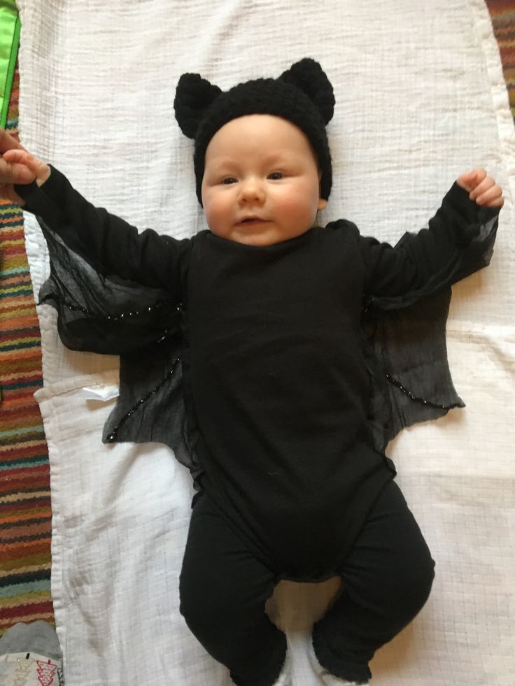 a baby dressed in black laying on top of a bed