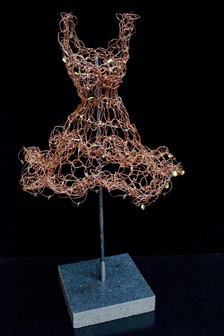 a sculpture made out of wire on top of a wooden block in the middle of a dark room