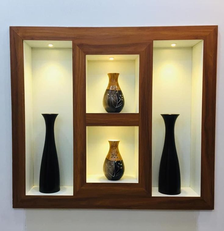 three black vases sitting in a wooden display case on the wall next to each other