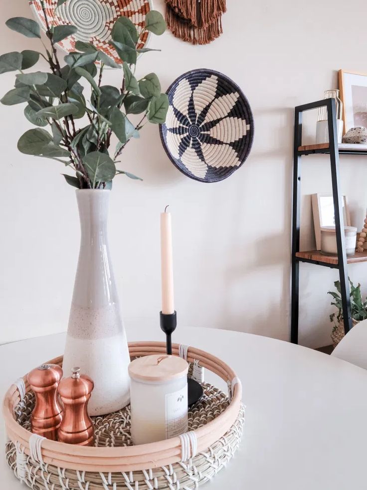 a white table topped with a vase filled with flowers next to a candle and other items