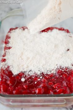 someone is adding white sugar to the cranberry sauce in a casserole dish