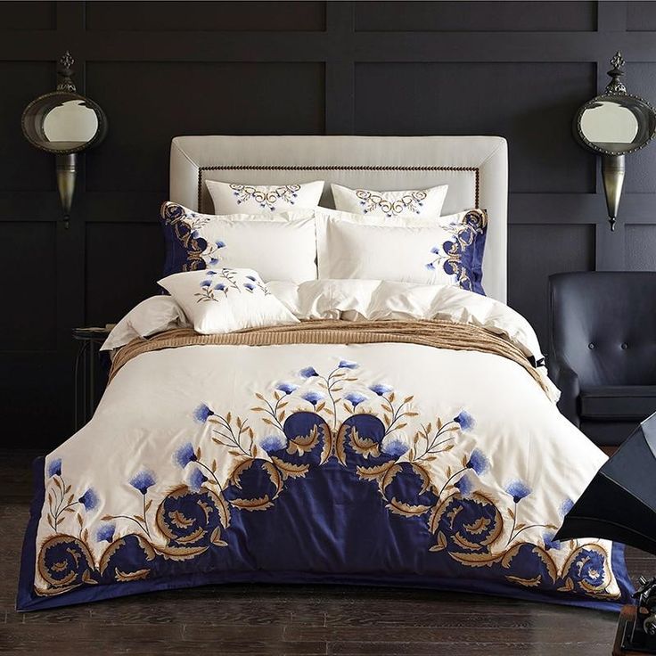 a large bed with blue and white comforters in a dark room next to a black wall