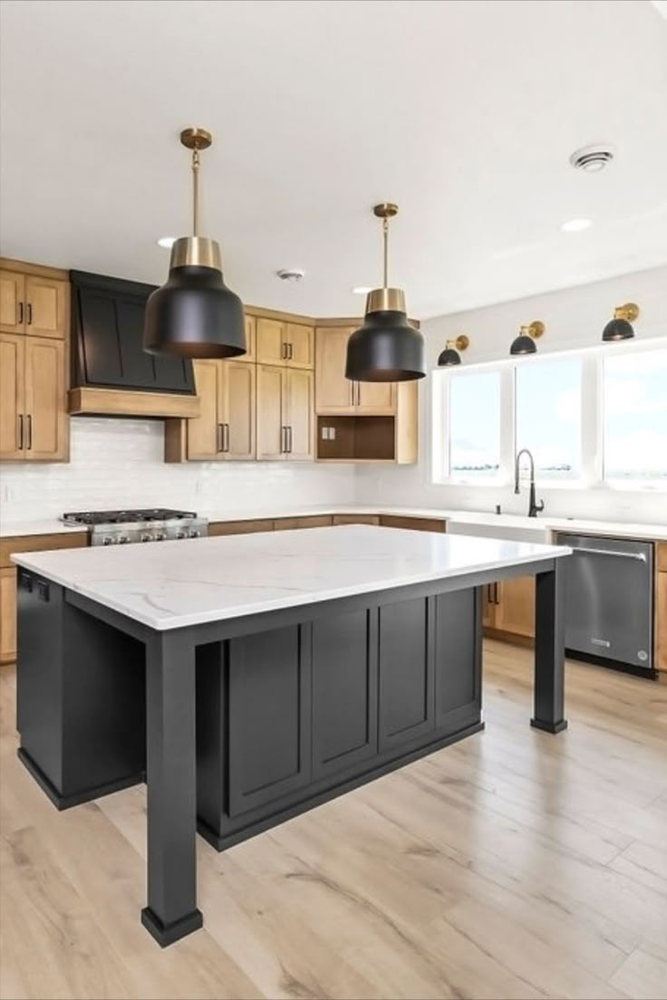 a large kitchen with an island in the middle and two lights hanging from the ceiling