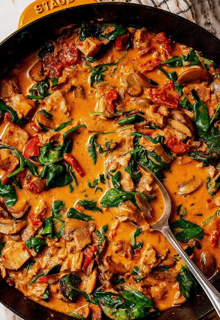 a skillet filled with chicken and spinach covered in sauce