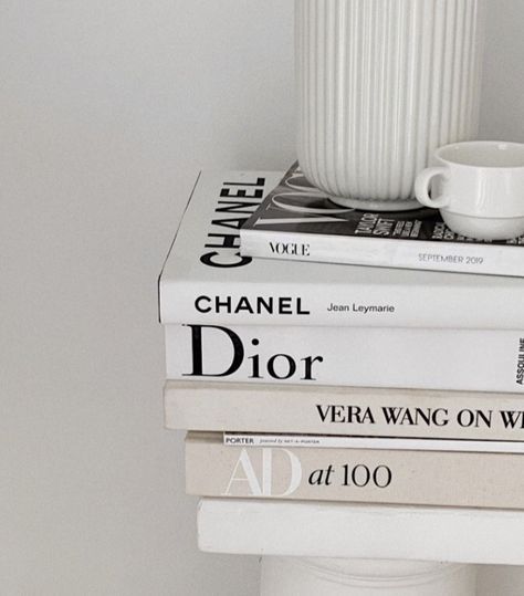 three books stacked on top of each other next to a white cup and saucer