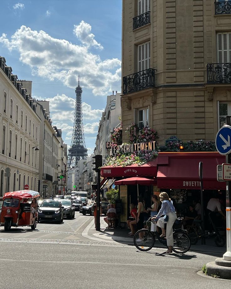 the eiffel tower is in the distance as people ride bikes down the street