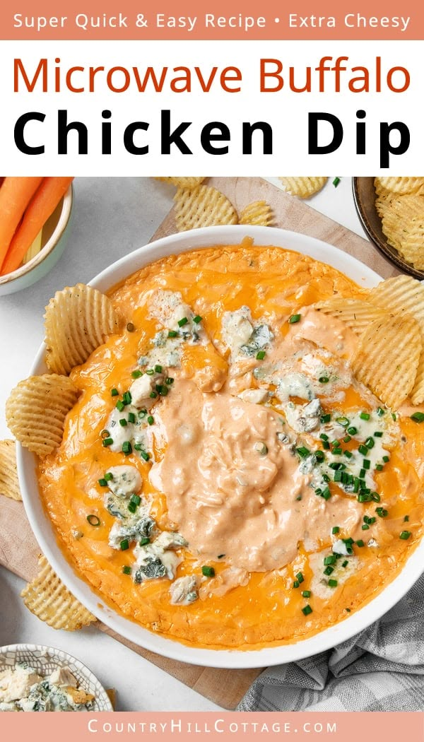 a white bowl filled with chicken dip surrounded by chips and carrots on the side