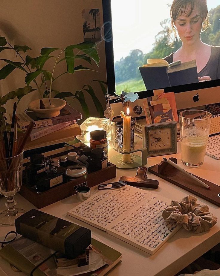 a desk with a computer monitor, keyboard and various items on it in front of a window