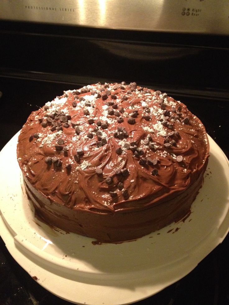 a chocolate cake sitting on top of a white plate in front of an open oven