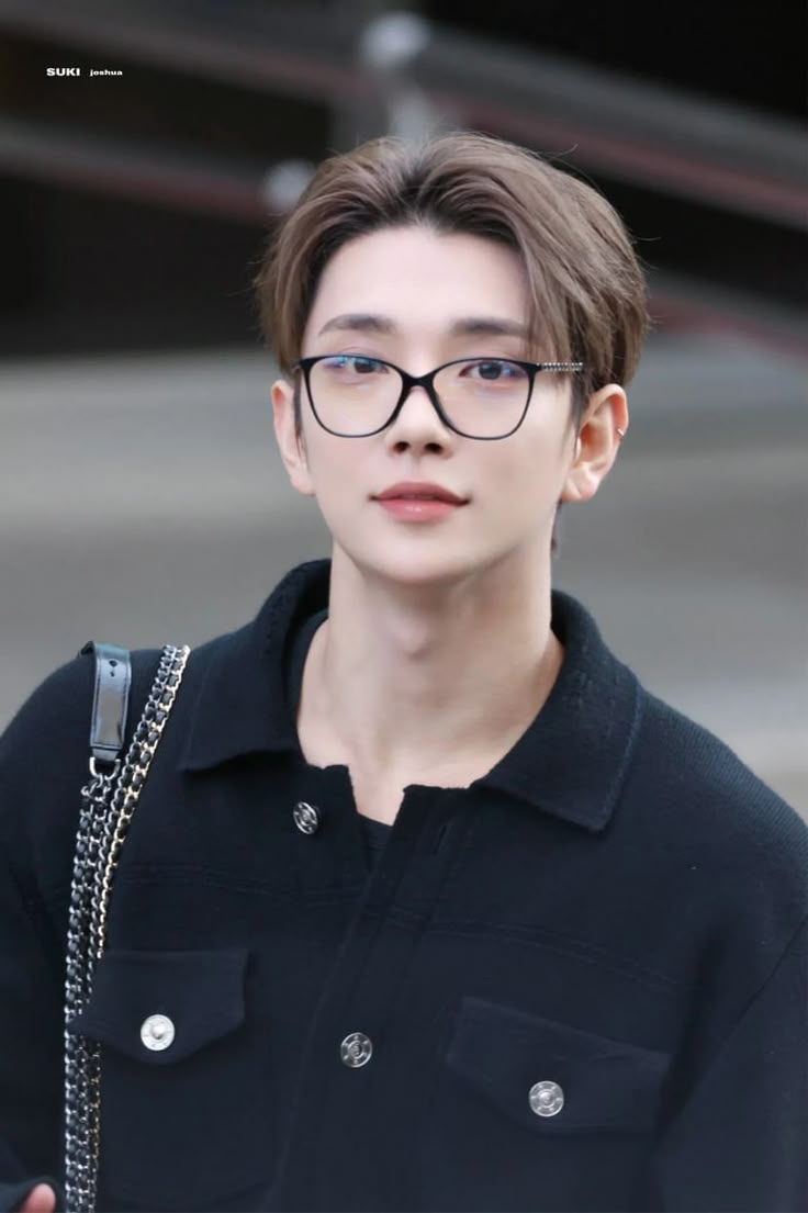 the young man is wearing glasses and carrying a handbag