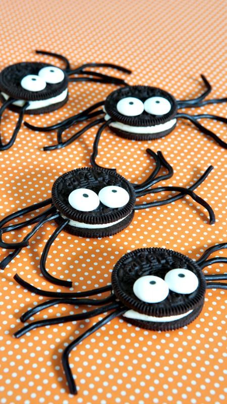 oreo cookies decorated with googly eyes on an orange tablecloth for halloween treats