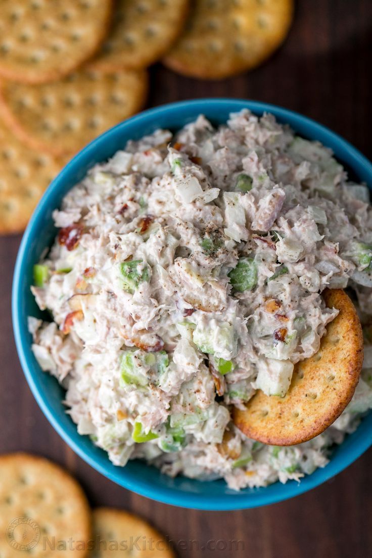 a blue bowl filled with chicken salad next to crackers