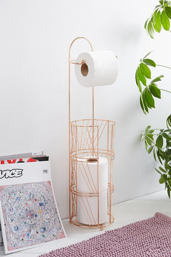 a magazine rack with two rolls of toilet paper on it next to a pink rug