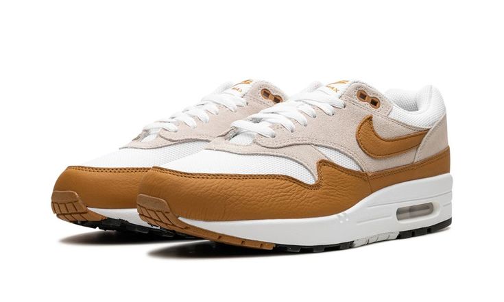 The Nike Air Max 1 SC "Bronze" is a colorway of the retro performance running shoe with an autumn-inspired look.  The “Bronze” rendition features a white mesh base with light grey suede overlays on the vamp, eyelets, mid-panel, and heel.  A Bronze leather Swoosh appears on each side of the shoe.  The autumn-esque hue is also found on the leather mudguard, as well as on the “Nike Air Max” branding on the tongue tag and “Nike Air” branding on the heel.  The shoe’s white foam midsole has a visible Bronze Shoes, Autumn Inspired, Nike Air Max 1, Stadium Goods, July 7, Grey Suede, White Mesh, Air Max 1, Gray Suede