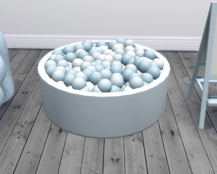 a large bowl filled with lots of balls on top of a wooden floor next to a chair