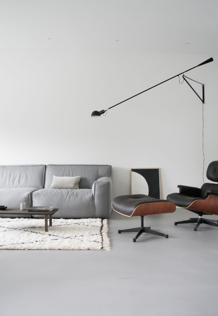 a living room with a couch, chair and lamp on the wall next to it