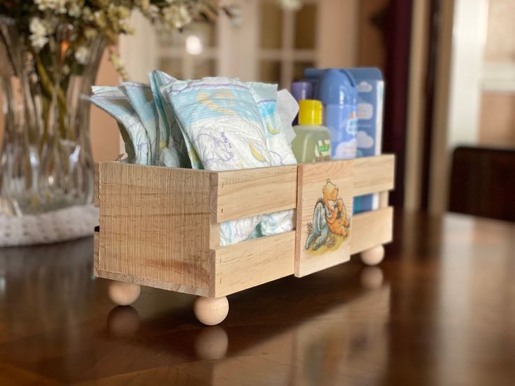 a wooden box with soaps and lotions in it sitting on a table next to a vase