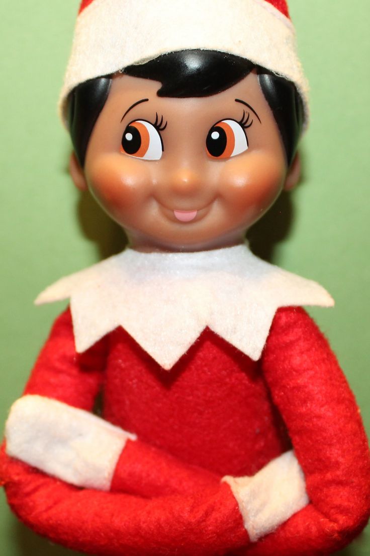 an elf doll wearing a red and white outfit with his arms crossed in front of him