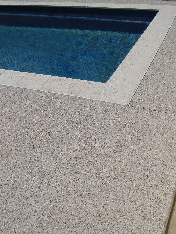 an empty swimming pool in the middle of a concrete floored area with blue water