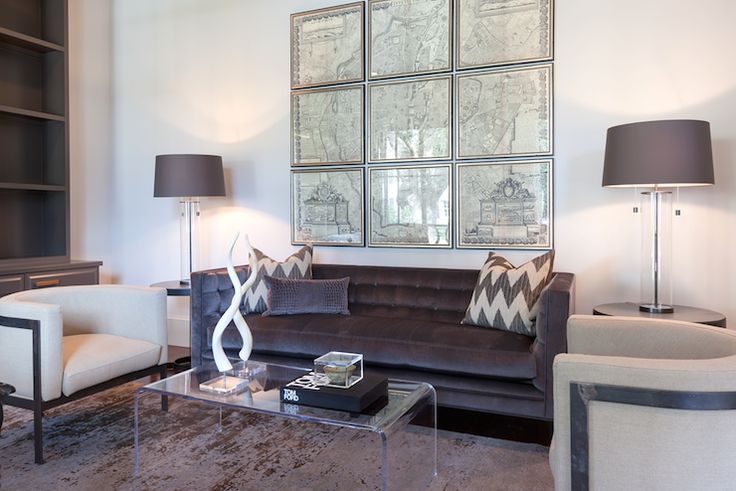 a living room with couches, chairs, lamps and pictures hanging on the wall