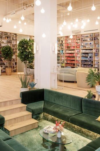 a living room filled with green couches and lots of books on the shelves behind them