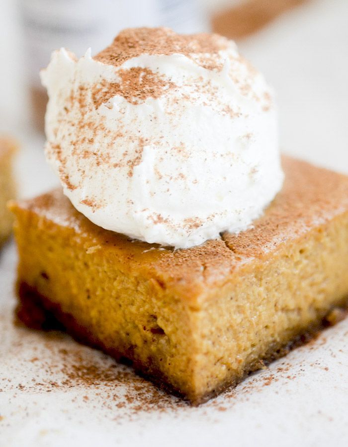 a piece of pumpkin pie with whipped cream on top is sitting on a white surface