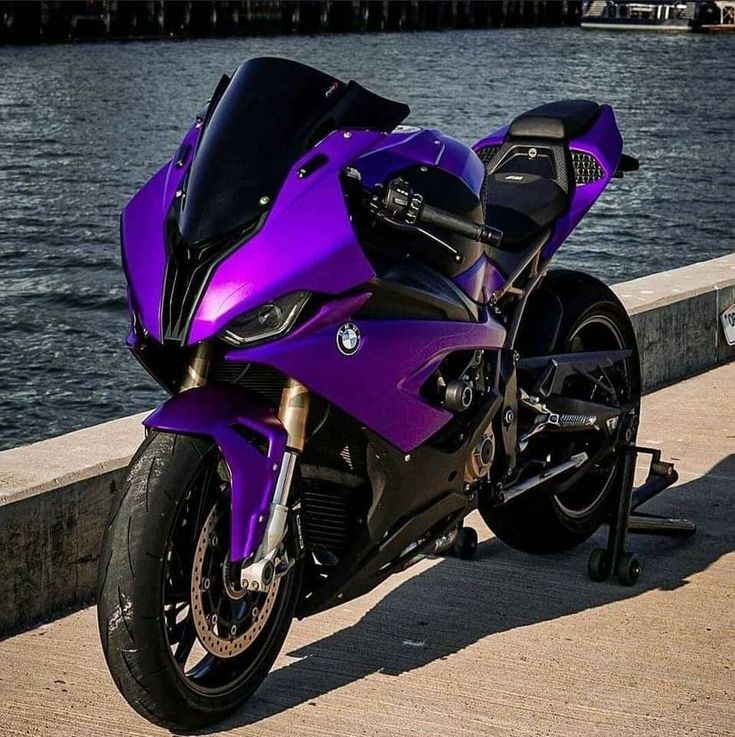 a purple motorcycle parked next to the water